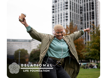 Person wearing headphones dancing outdoors in a city park