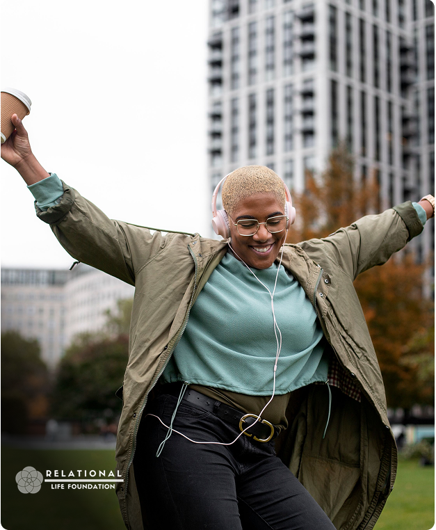 Person wearing headphones dancing outdoors in a city park
